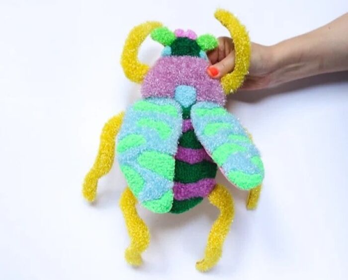 A handmade tufted beetle art piece held by Ina Dyreborg