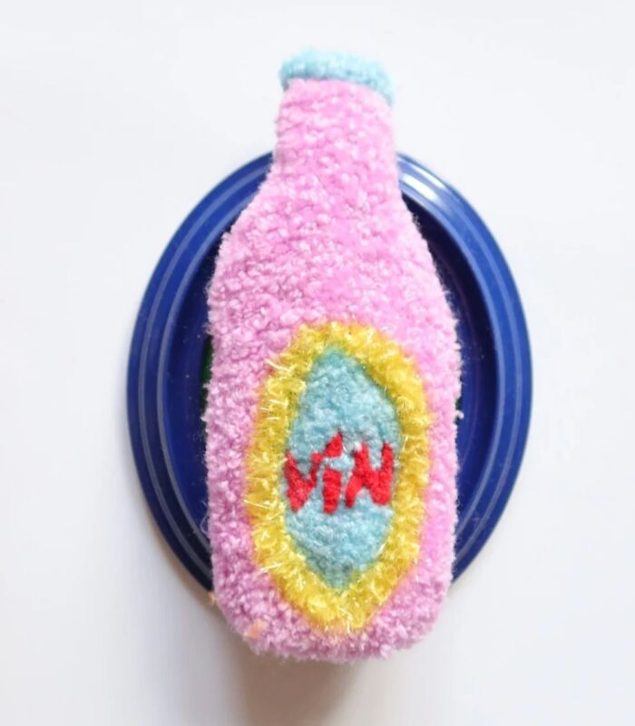 Tufted pink wine bottle artwork on a blue base by Ina Dyreborg
