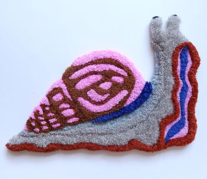 A colorful tufted textile art of a snail by Ina Dyreborg