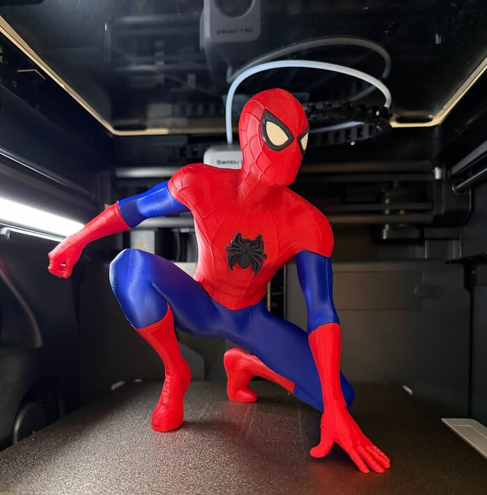 A detailed red and blue Spider-Man figure created with 3D prints inside a printer