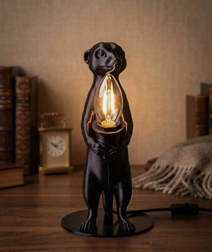 A creative meerkat lamp made using 3D prints on a wooden desk.