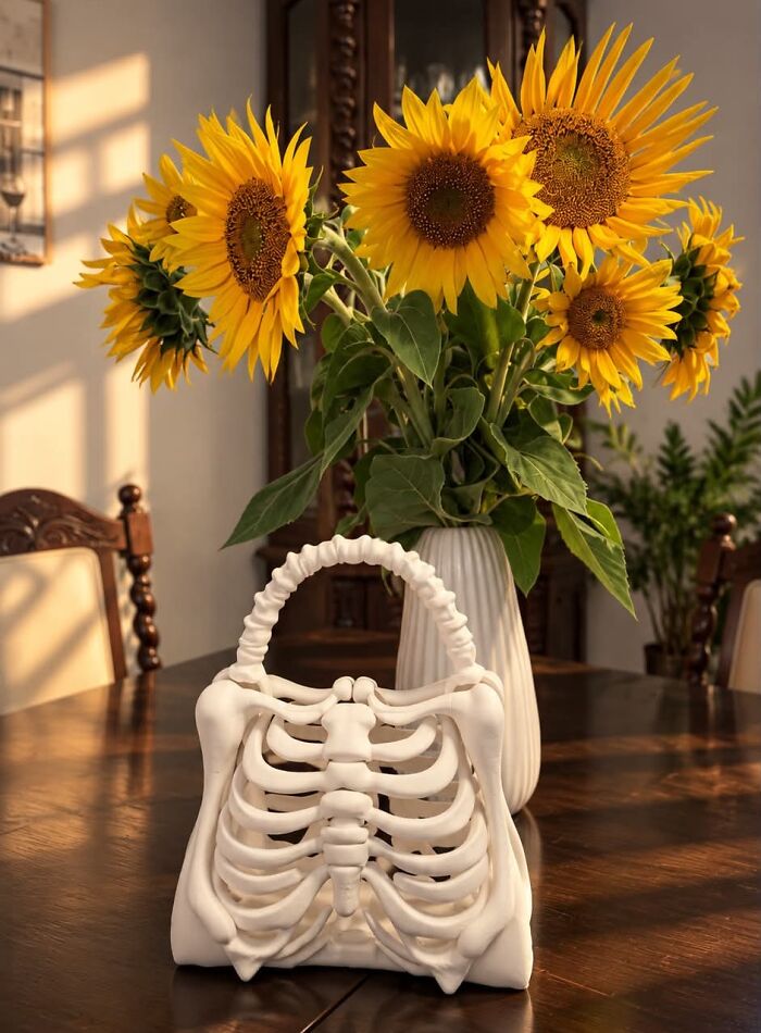 A white rib cage design purse standing on a table near sunflowers, highlighting unique 3D prints