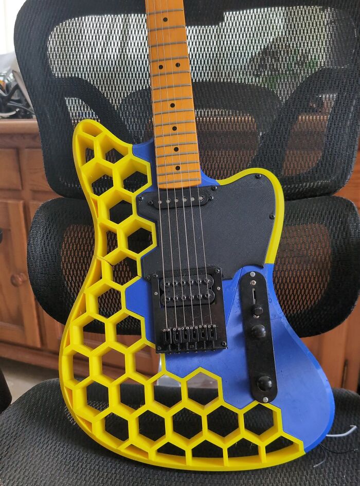 An electric guitar featuring a unique yellow honeycomb pattern made with 3D prints