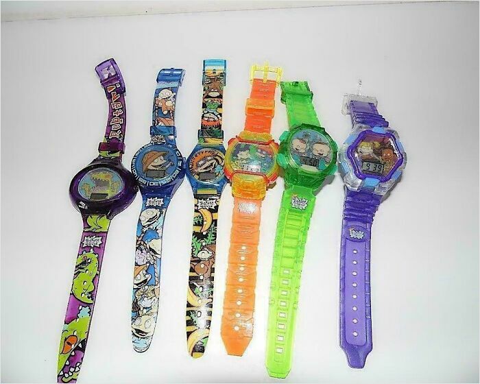 Six colorful plastic Rugrats wristwatches shown in nostalgic images of 90s kids merchandise.