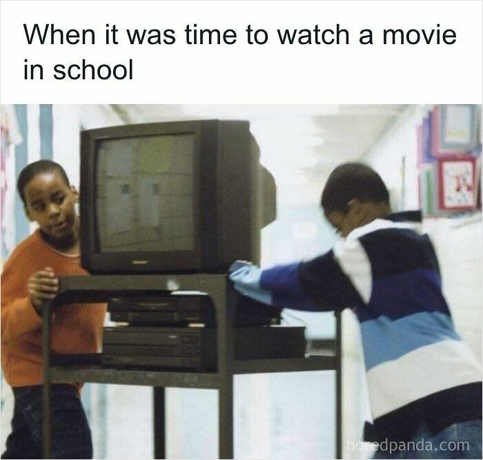 Two kids pushing a heavy CRT television cart down a school hallway, a nostalgic sight for 90s kids