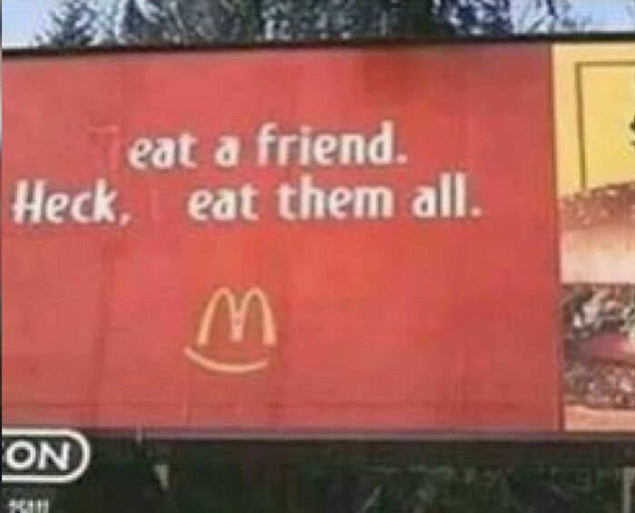 Humorous vandalism on a McDonald's billboard where the letter T is blacked out to say Eat a friend