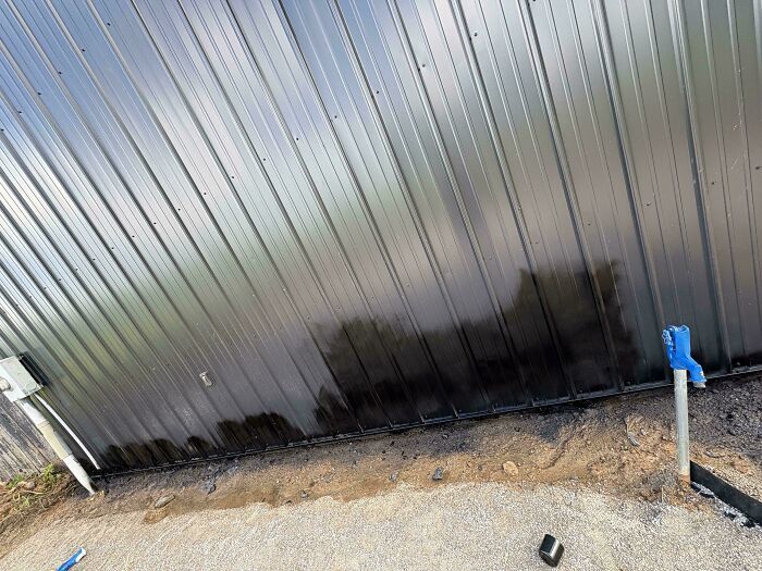 A black metal wall stained at the bottom during a botched attempt to improve and renovate their homes.