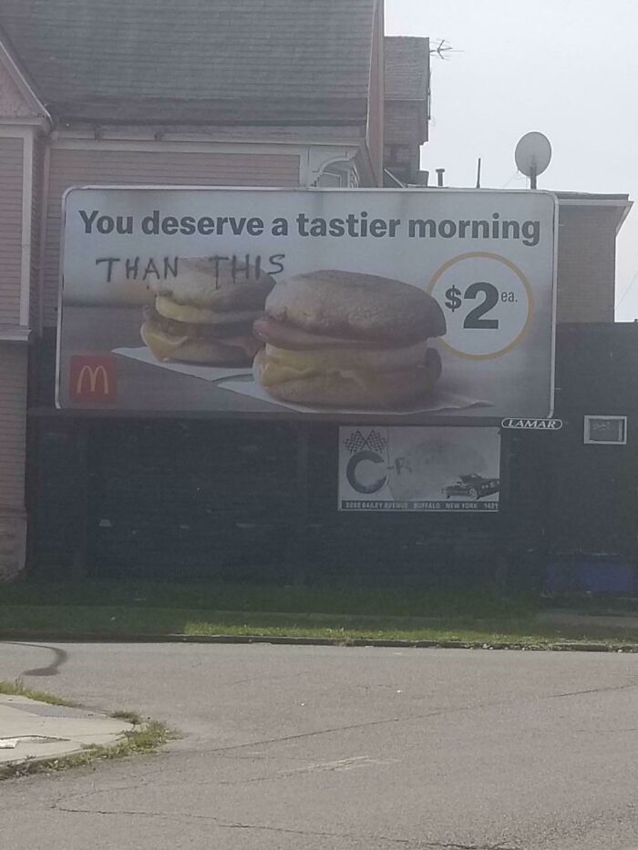 Clever vandalism on a fast food breakfast billboard adding humorous graffiti critique