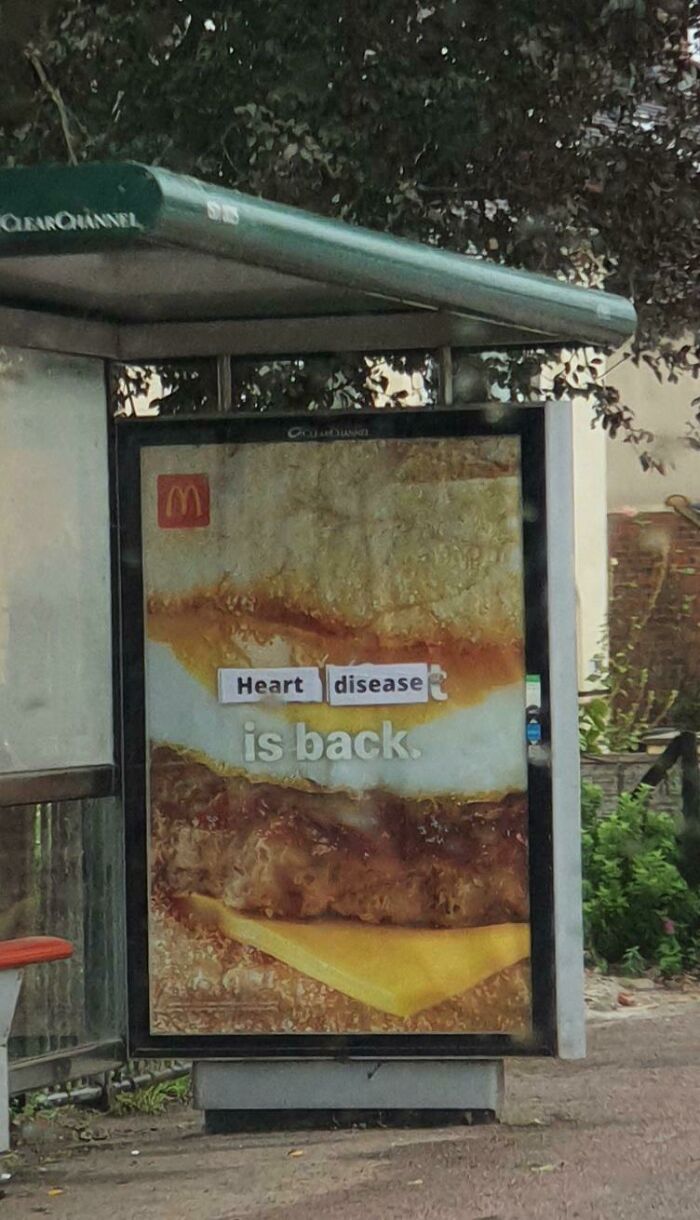A bus stop fast food ad stickered to read Heart disease is back, showing a clever act of vandalism as public art.