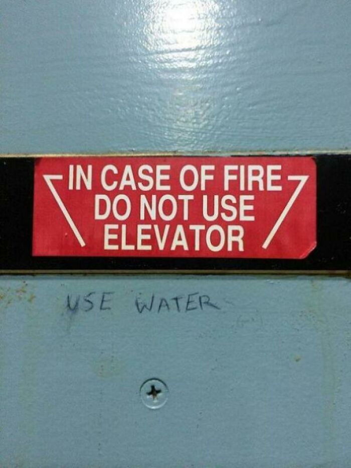 Clever vandalism on fire sign that reads Use Water, showing humor and public art style.