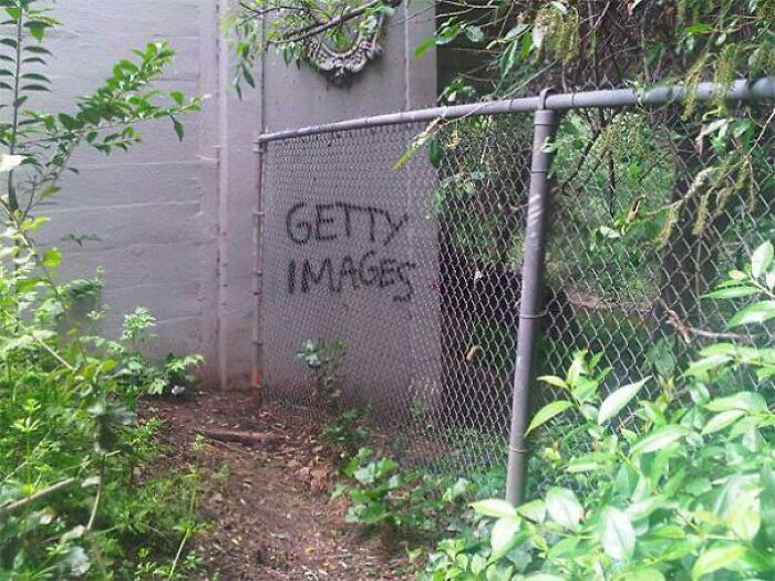 Humorous graffiti vandalism with Getty Images written in black paint on a chain-link fence
