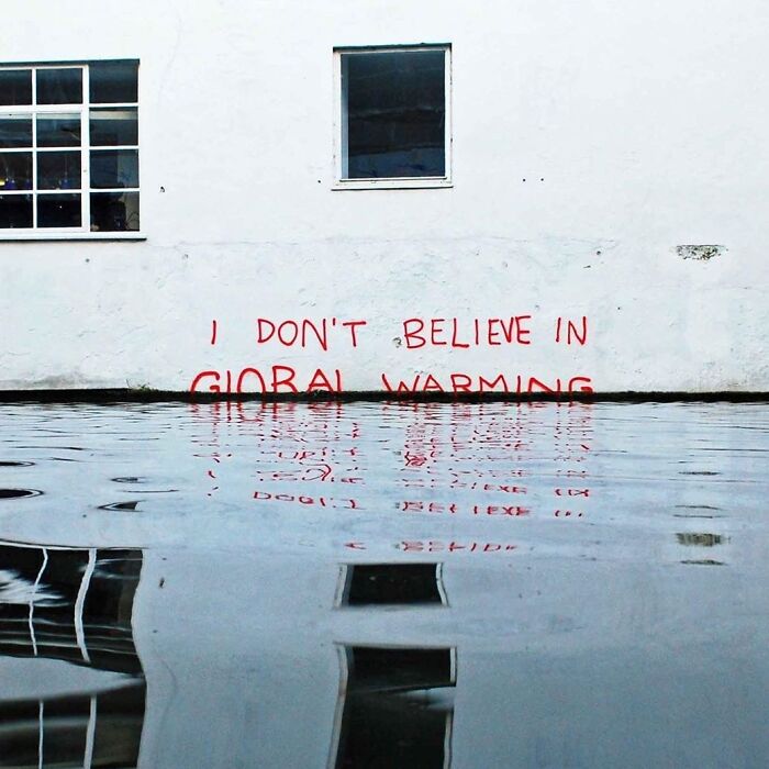 Clever vandalism showing I DON'T BELIEVE IN GLOBAL WARMING graffiti half-submerged in rising water