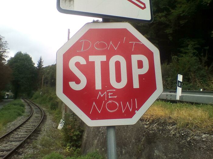 A red stop sign with handwritten graffiti reading Don't Stop Me Now!, illustrating a musical act of vandalism.