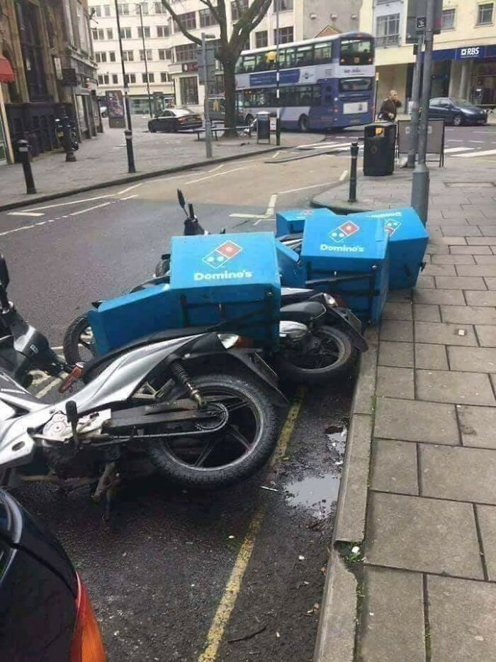 Clever public art layout of fallen Dominos delivery scooters mimicking actual dominoes.