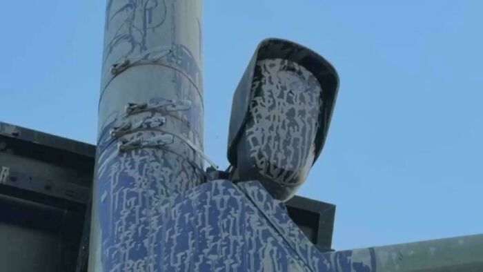 Public art vandalism featuring a speed camera covered in paint to look like a masked figure.