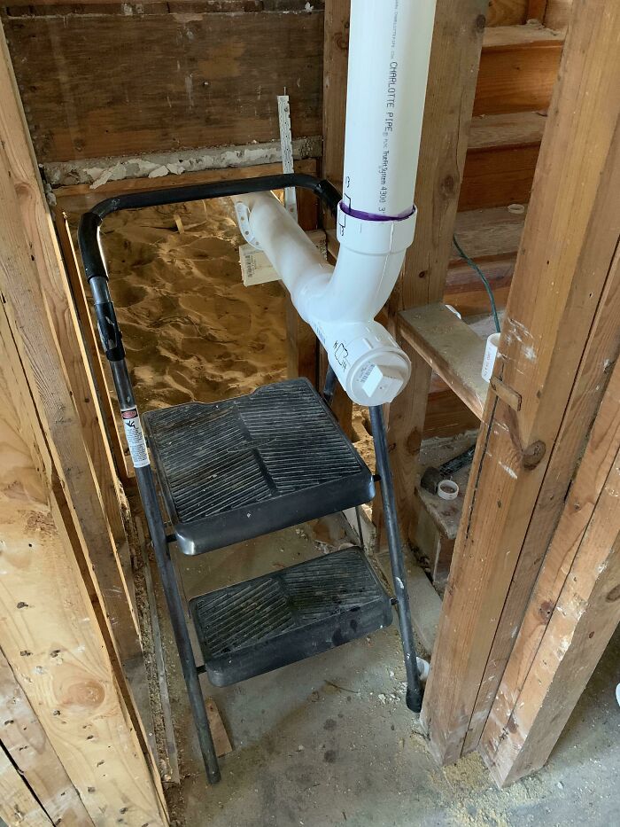 A white PVC pipe oddly routed through a black step ladder, showing a complete fiasco in home renovation.