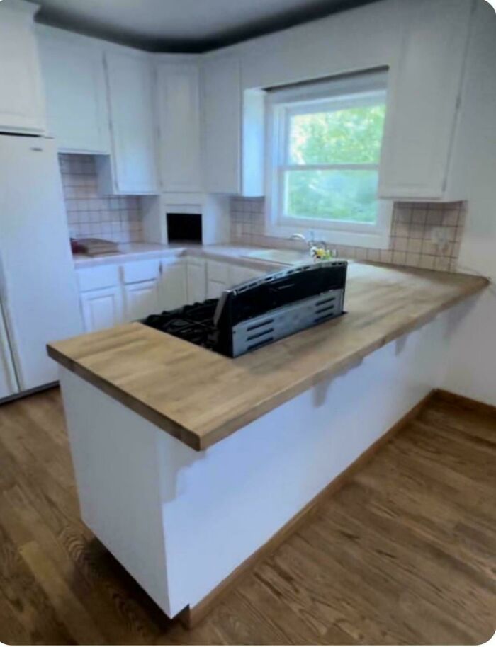 An awkwardly placed stove on a wooden countertop kitchen island during a home renovation.