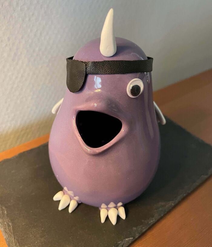 A cute purple ceramic creature with an eyepatch, representing whimsical thrift store finds.