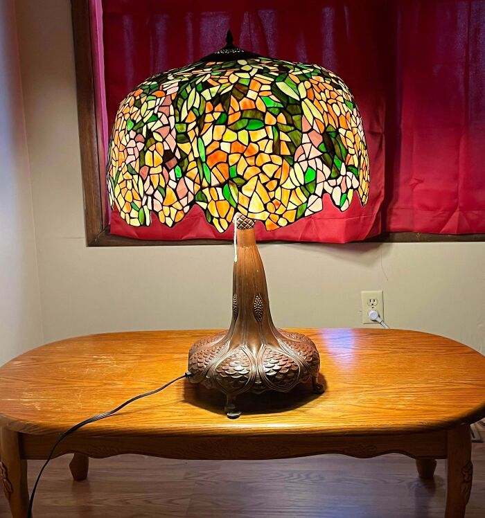 An exquisite stained glass Tiffany-style table lamp glowing on a wooden table, a thrift store find