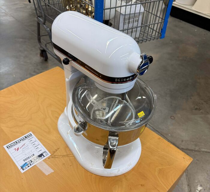 A white KitchenAid stand mixer sitting on a wooden table, one of the best thrift store finds.