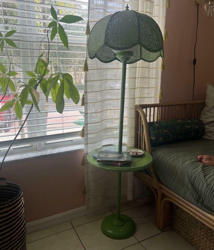 A green floor lamp with a built-in small table and woven shade, styled as cozy thrift store finds.