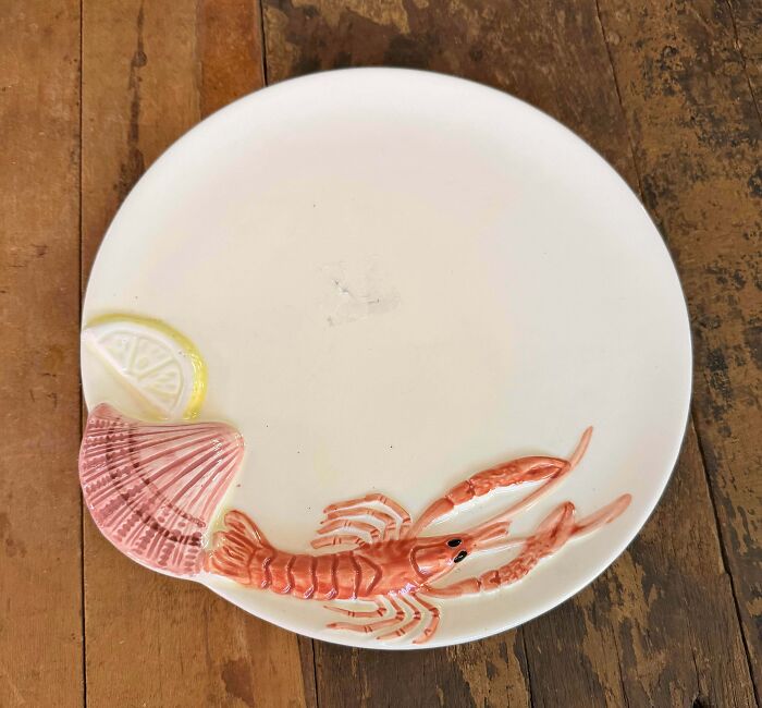 A white ceramic plate with a raised lobster design, one of the unique thrift store finds.
