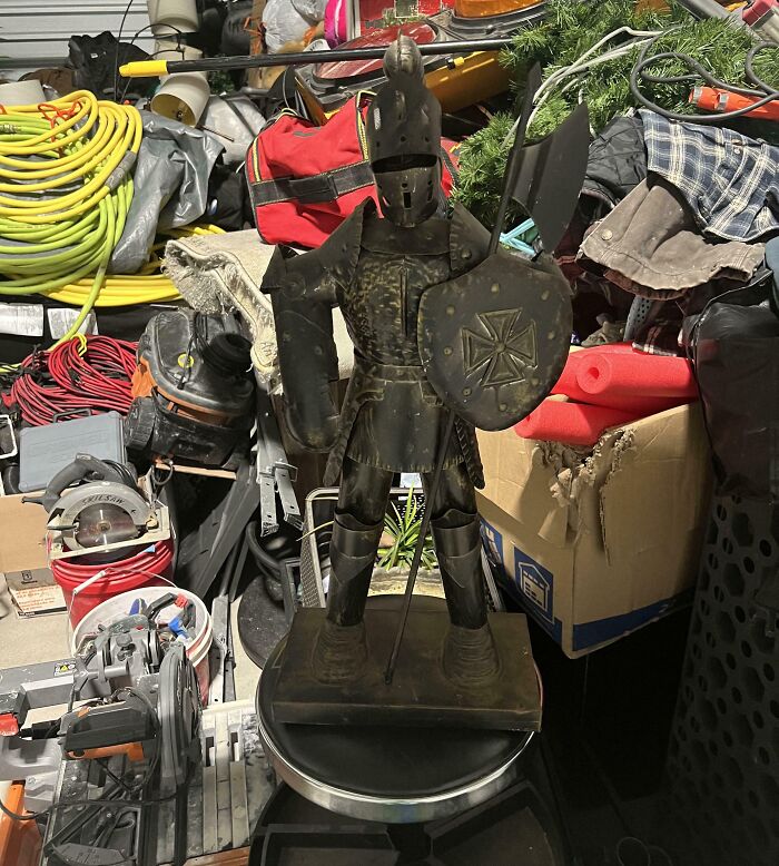 A miniature decorative metal knight statue holding a shield, among unique thrift store finds.