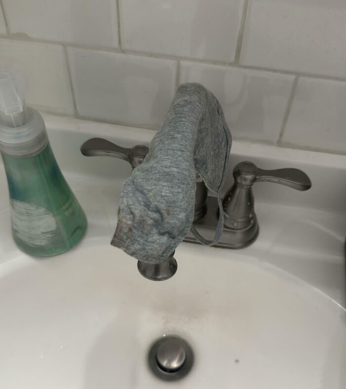 A dirty cloth mask left hanging on a bathroom sink faucet in funny roommate stories