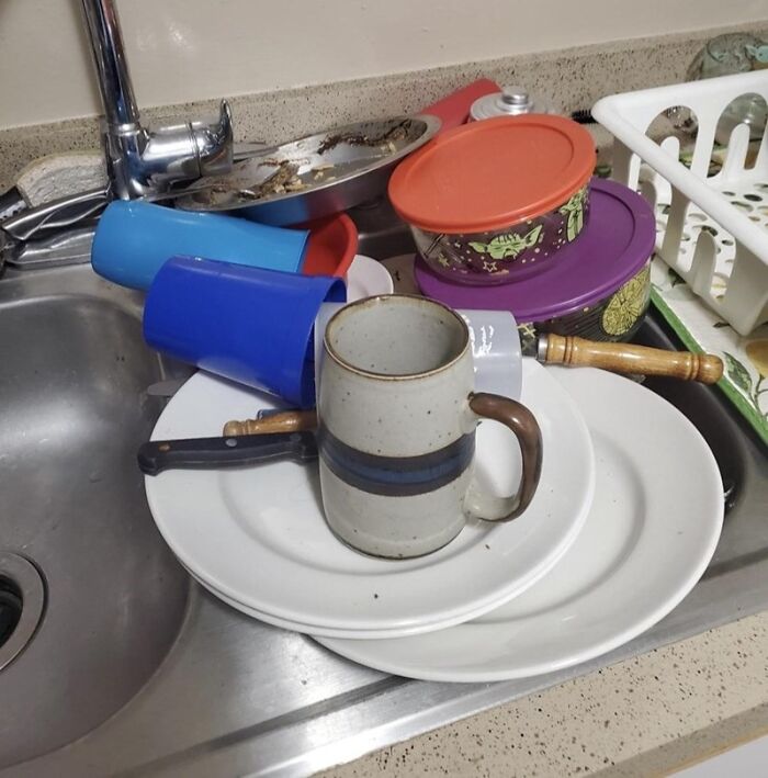 A pile of dirty dishes and cups left in a kitchen sink, showing common roommate stories of messy habits