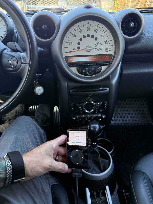 An old iPod classic playing music connected inside a car, perfect for vintage tech finds