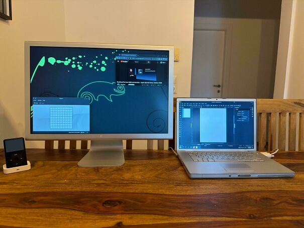 A classic setup of vintage tech with a chunky monitor, silver laptop, and an iPod on a wooden desk