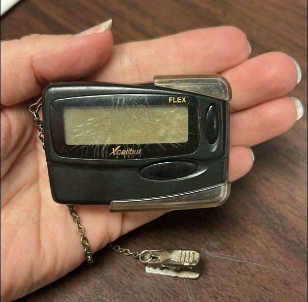 A black vintage pocket pager held in a hand, showcasing iconic vintage tech finds