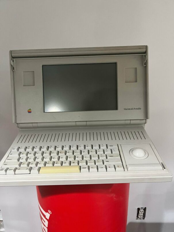 A vintage tech Macintosh Portable laptop computer with its built-in trackball and keyboard