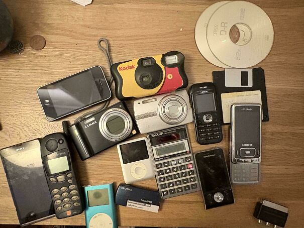 A collection of vintage tech items including flip phones, classic iPods, old digital cameras, and floppy disks