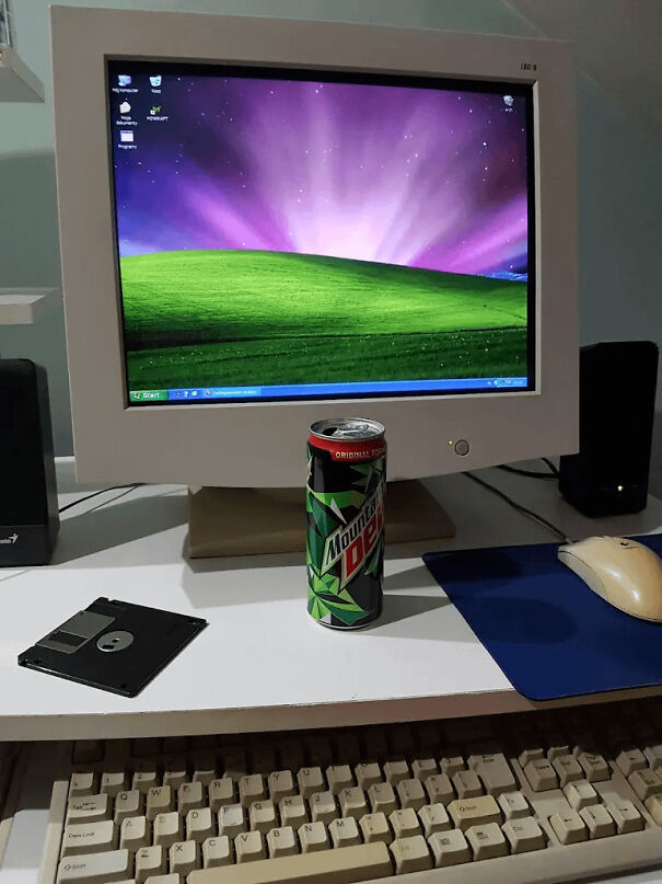 An old CRT monitor with the classic Windows XP background next to a floppy disk, showing classic vintage tech.