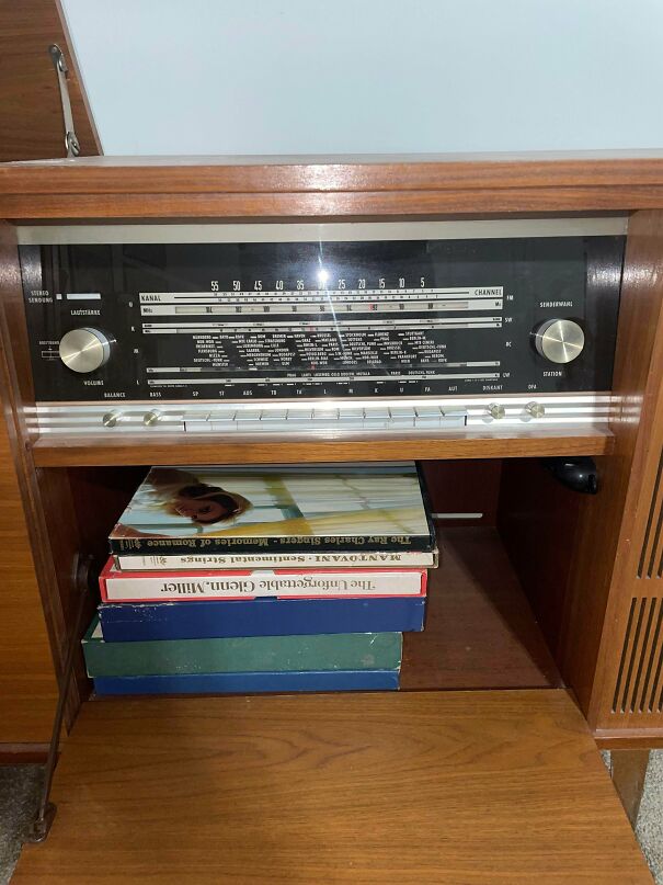 Vintage tech console with a classic built-in radio dial and a shelf holding old music records