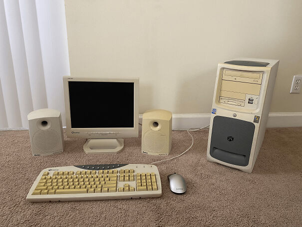 A set of beige chunky electronics including an old computer monitor, keyboard, tower, and speakers on a carpet.