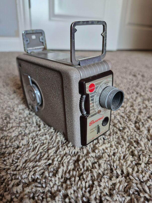 A vintage tech Kodak Brownie movie camera sitting on a carpet