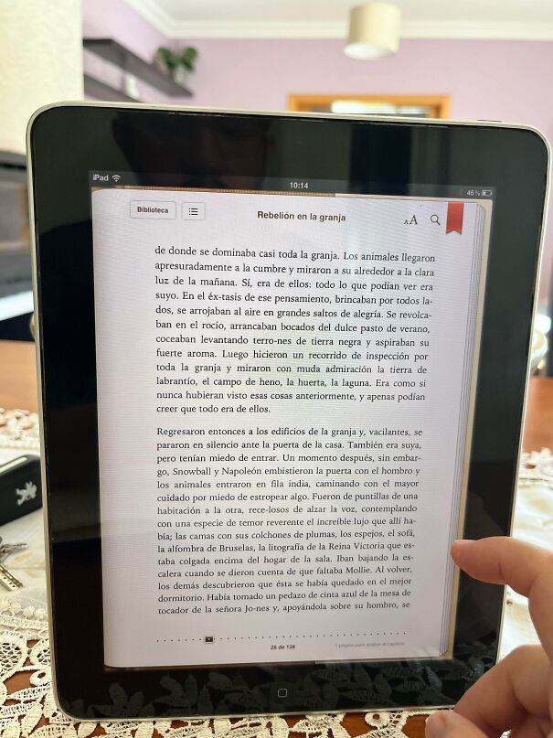 A hand holding an old iPad displaying an e-book in Spanish, showcasing vintage tech.