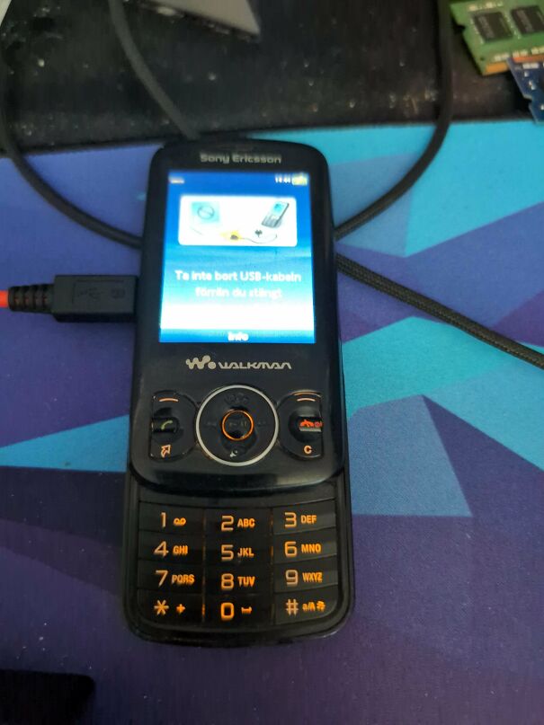 A classic Sony Ericsson Walkman phone as a vintage tech relic connected to a cable