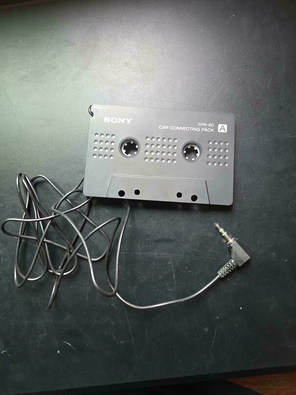 Vintage tech Sony cassette adapter with auxiliary cord on dark surface