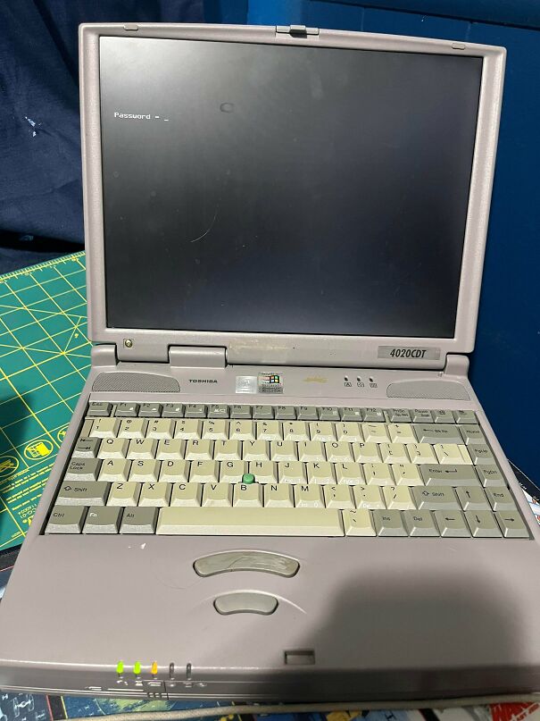 A vintage Toshiba 4020CDT laptop open to a command prompt password screen, highlighting chunky retro electronics