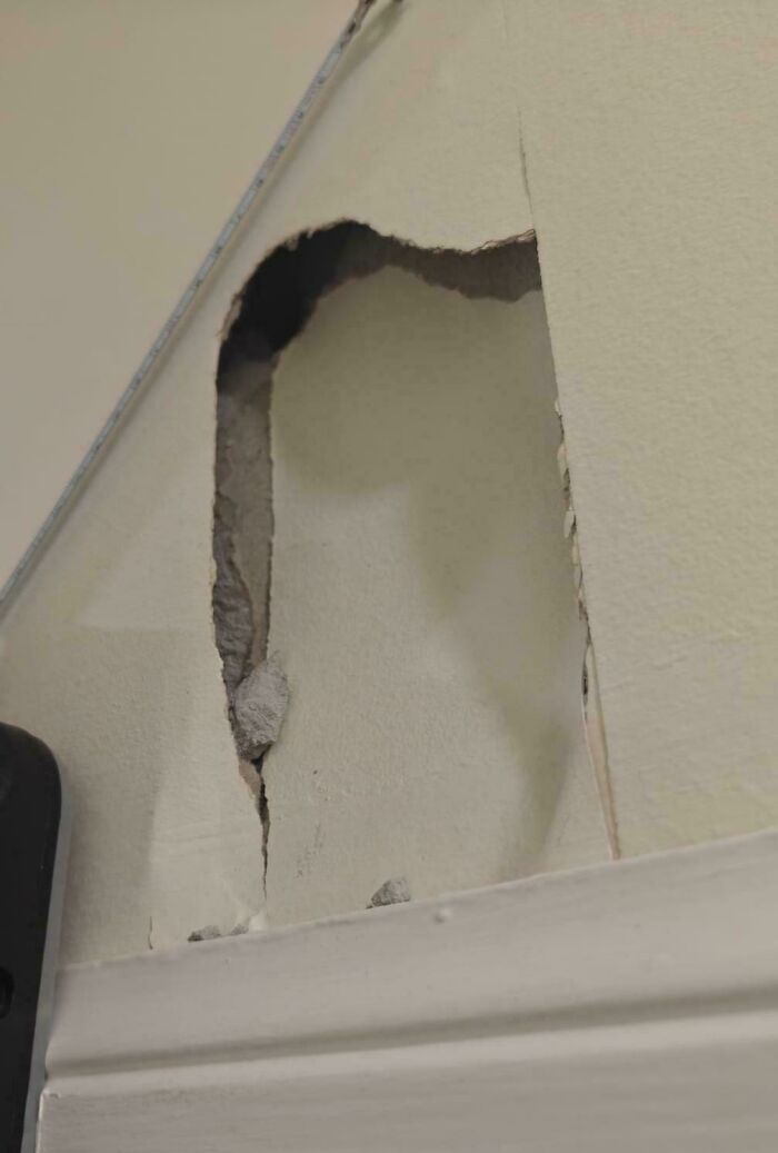 A questionable decision depicting a damaged wall with plaster broken and peeling near a white trim