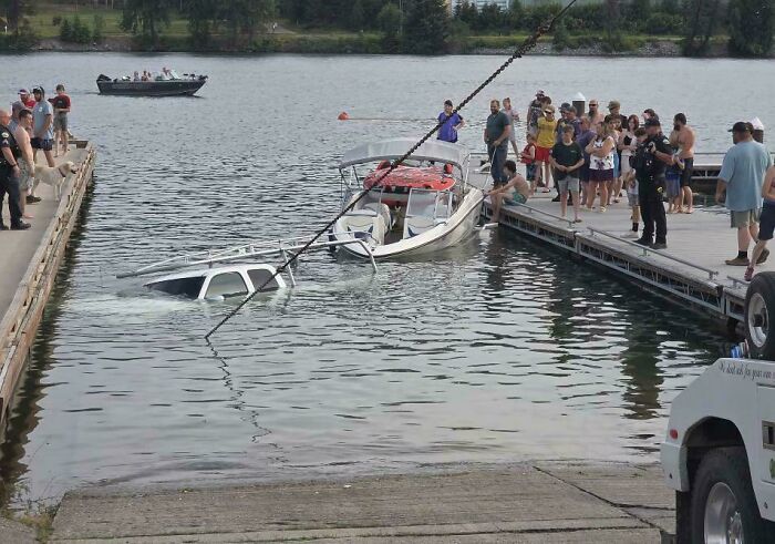 A white truck submerged in water next to a boat dock showcasing a questionable decision at the boat launch