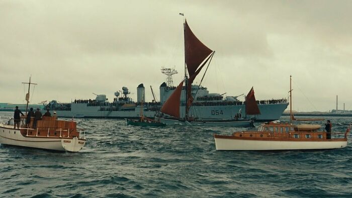 Several small boats and a large battleship in the water, showcasing realistic movie props.