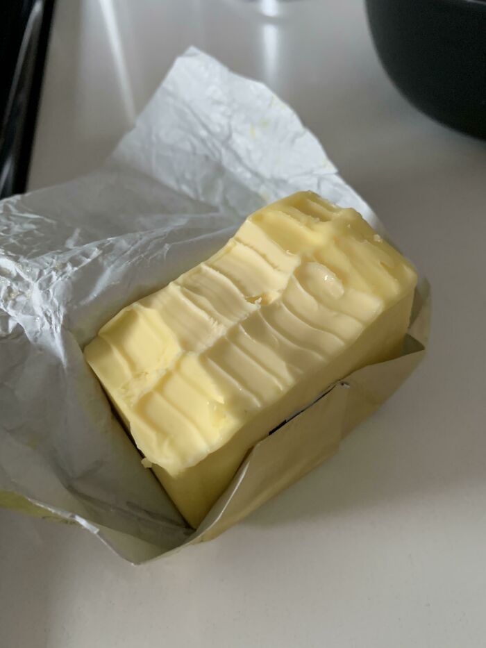 An opened block of butter with a questionable decision showing bite marks directly on the stick.