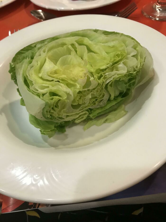 A questionable food prep decision showing a large, uncut wedge of iceberg lettuce served plain on a plate.