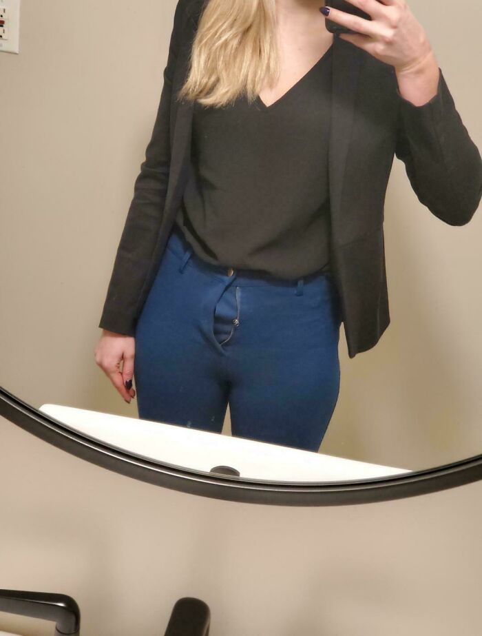 A woman wearing blue pants with an open fly zipper, showing a questionable fashion choice