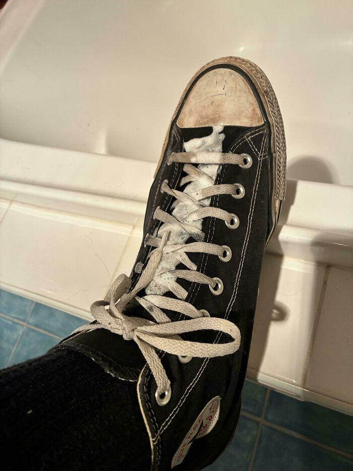 Toothpaste spilled all over the laces of a black sneaker, showing questionable decisions