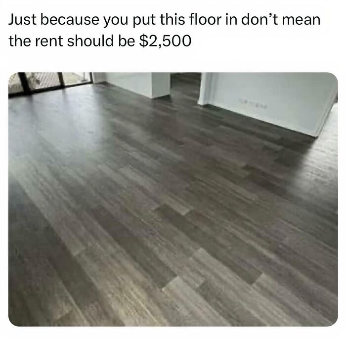 Grey laminate flooring in an apartment mocking terrible landlords who overcharge rent for cheap renovations.